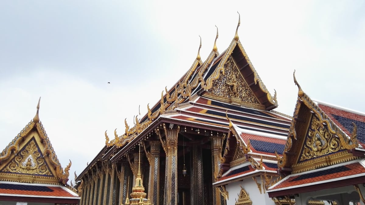 A grand Thai temple with intricate golden decorations and multi-tiered roofs.