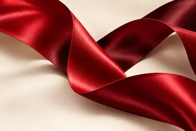 Glossy red satin folds twist across a pale cream background.