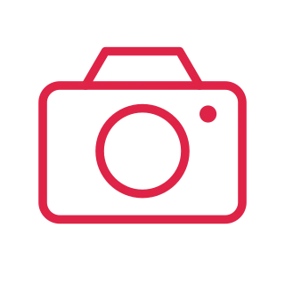 A camera body has a stepped top, circular lens and a small indicator light.