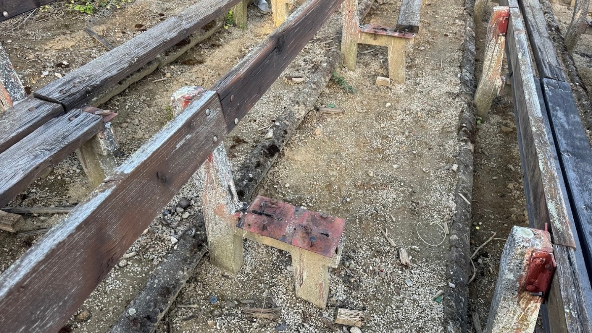 Old, broken wooden benches in an outdoor seating area, showing signs of decay and abandonment.