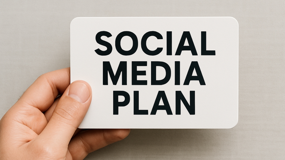 A hand holds a white card with bold black text that reads “Social Media Plan” against a neutral background.