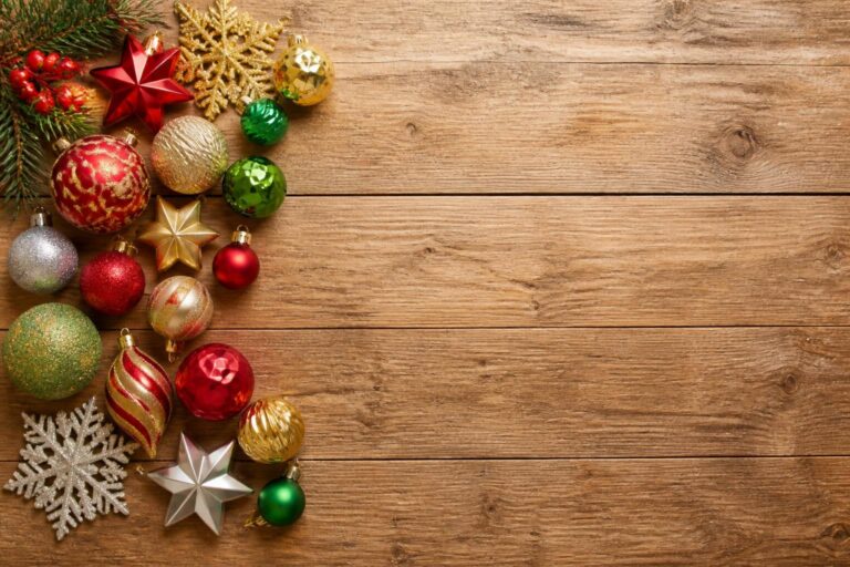 Colorful Christmas ornaments and decorations arranged on the left side of a wooden background