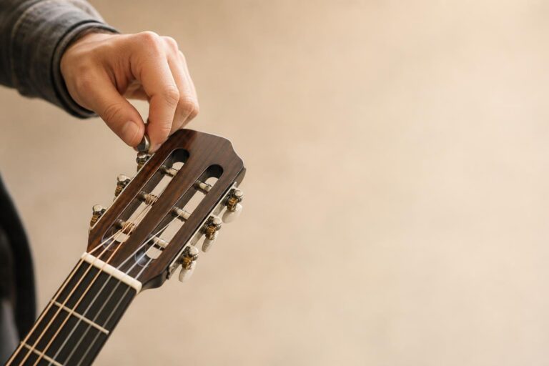 Hand tuning the peg of a classical guitar headstock with strings and tuning keys visible